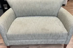 Gray fabric armchair with dull soiled seat cushion before a couch cleaning near me appointment in Raleigh, NC
