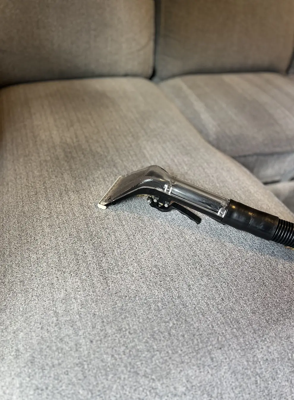 Fabric couch cleaning in progress in Atlanta, GA with a professional upholstery extraction tool, illustrating the founder’s hands-on approach and early company growth.