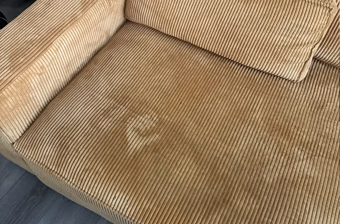 Corduroy fabric couch seat cushion with visible stains and discoloration before deep steaming upholstery cleaning in Raleigh, NC.