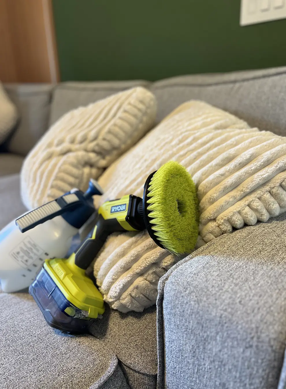 Upholstery brush and spray bottle placed on a sofa as part of a real couch cleaning setup, illustrating the early hands-on beginning of the Couch Steamers business.