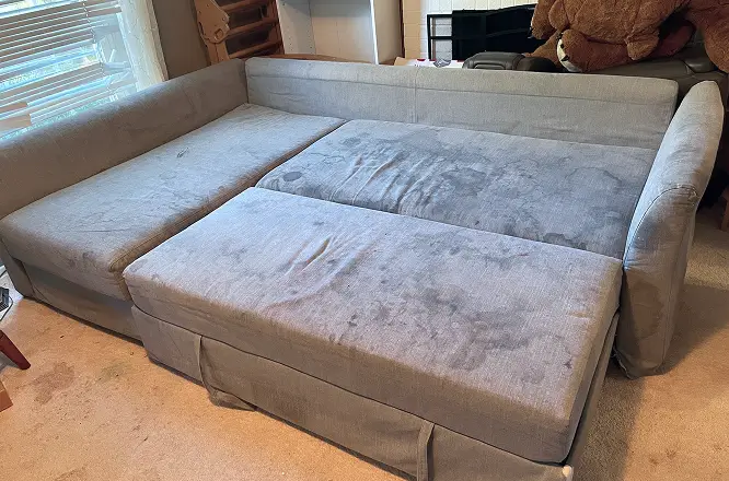 Large sectional couch with visible heavy dirt and darkened seating areas before professional couch cleaning in Raleigh, NC.