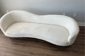 White curved sofa with pet stains and gray traffic marks before professional sofa cleaning near me in Raleigh