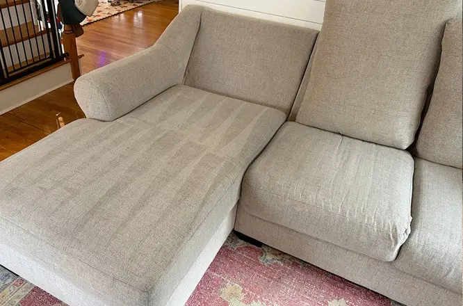 Light sectional couch chaise after deep stain removal and upholstery cleaning with noticeably cleaner fabric surface.