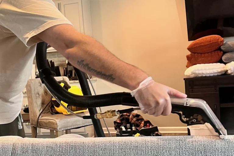 Technician performing professional steam upholstery cleaning with extraction tool to remove common couch stains