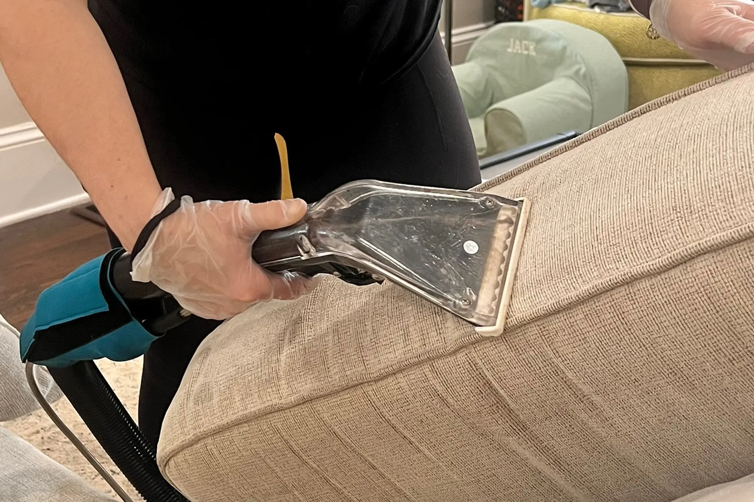 Professional couch cleaning technician using a steam extractor for eco friendly upholstery cleaning to permanently remove pet odor from a gray sectional sofa