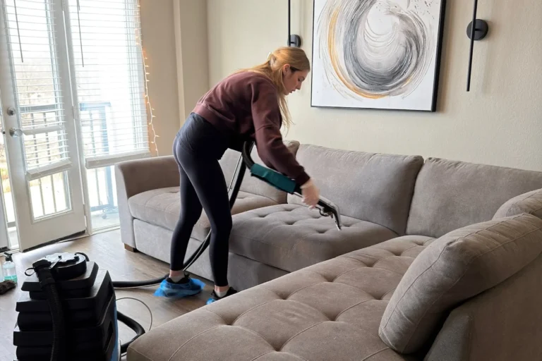 Professional couch cleaning technician using a steam extractor for eco friendly upholstery cleaning to permanently remove pet odor from a gray sectional sofa