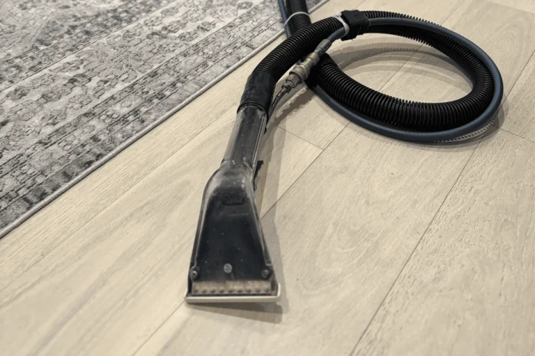 Professional upholstery cleaning technician using a steam extraction wand and hose during a couch cleaning service appointment