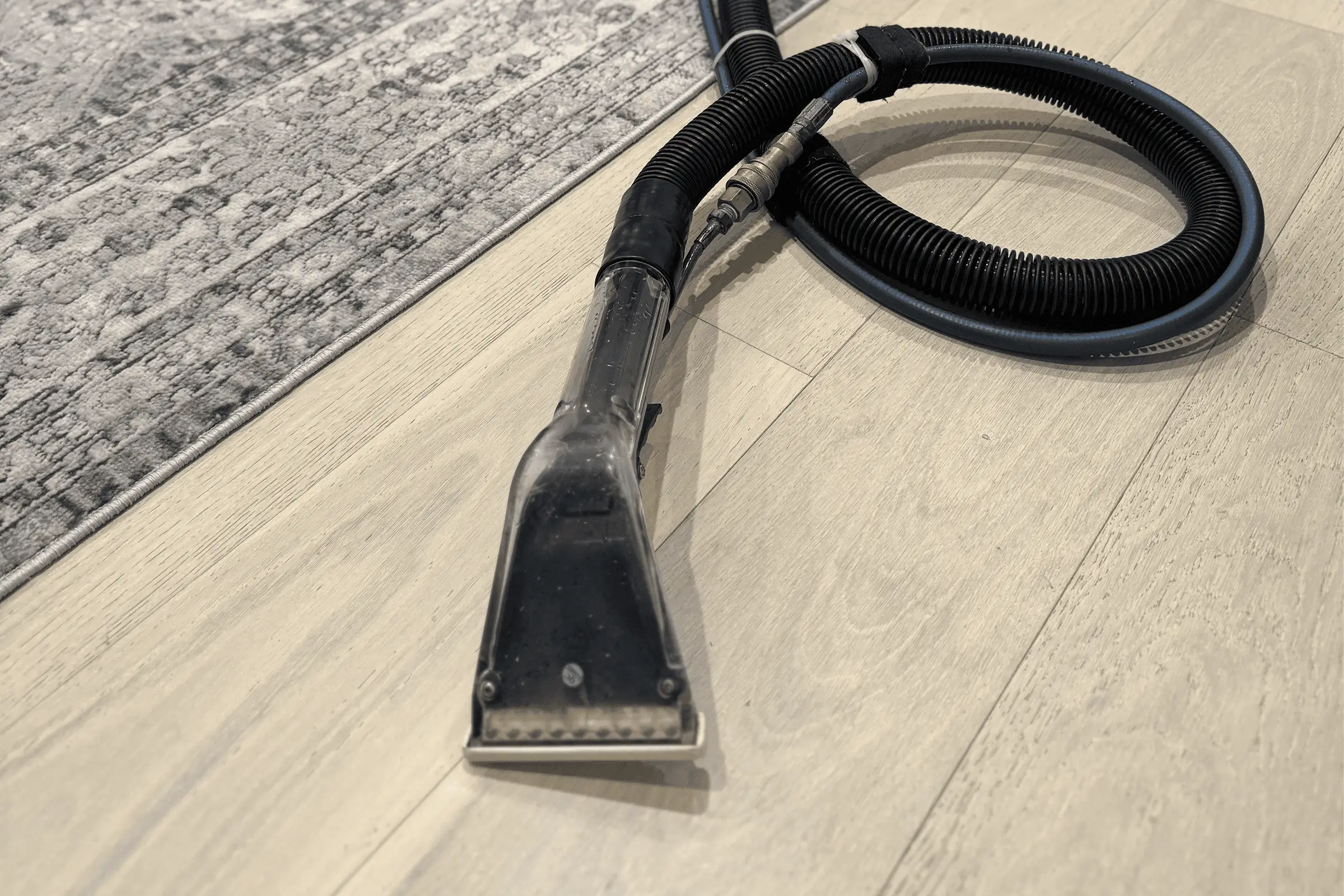 Professional upholstery cleaning technician using a steam extraction wand and hose during a couch cleaning service appointment