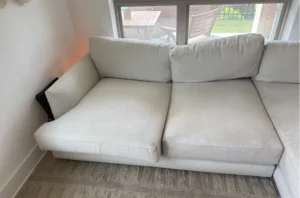 White sectional sofa with set in old stains before upholstery fabric cleaning in Denver, CO by our couch cleaning team.