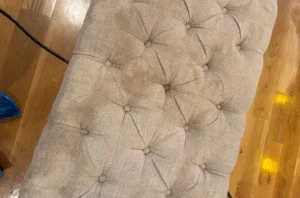 Tufted bench seat before chair cleaning, with old stains and grime settled deep into the button tufts.