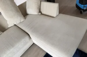 Same beige sectional after couch cleaning, with old stains lifted and the fabric looking soft, even, and fresh again.