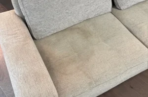 Light gray textured sofa with dull traffic marks and body soil before deep upholstery clean by our team