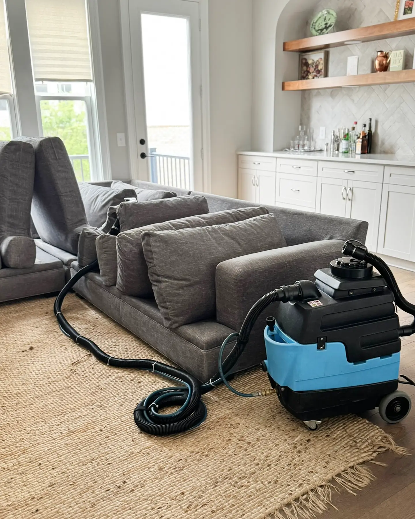 Couch Steamers extractor beside a gray fabric sectional before sofa cleaning in a bright Portland home