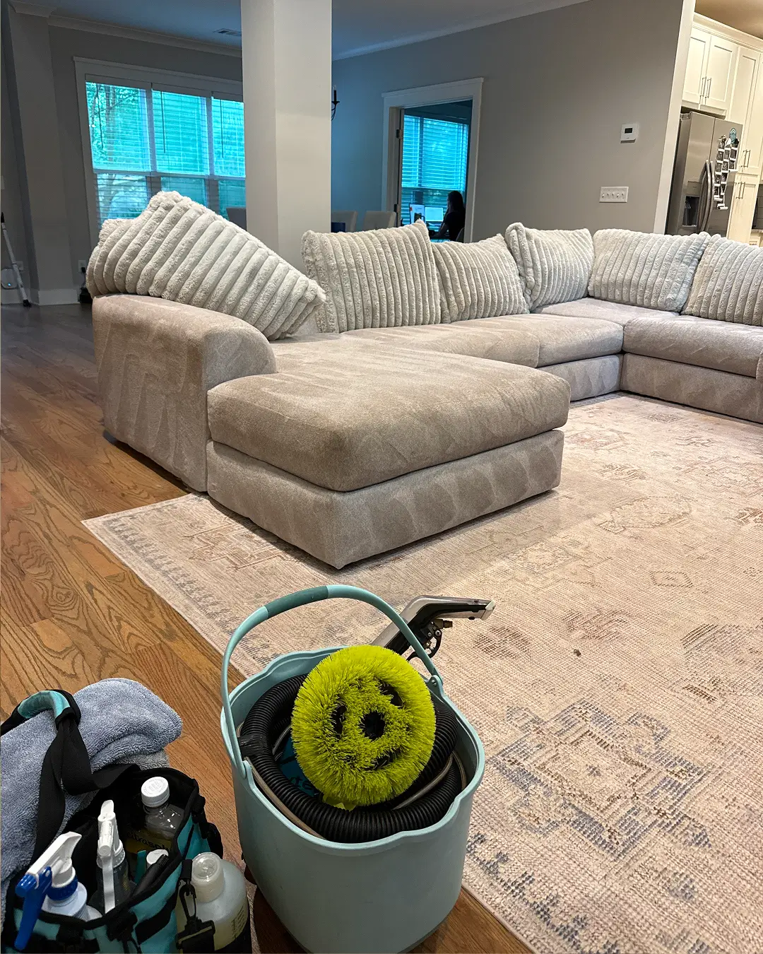 Couch Steamers gear by a freshly cleaned gray sectional and rug. Trusted couch cleaning for a fresh, spotless living room.
