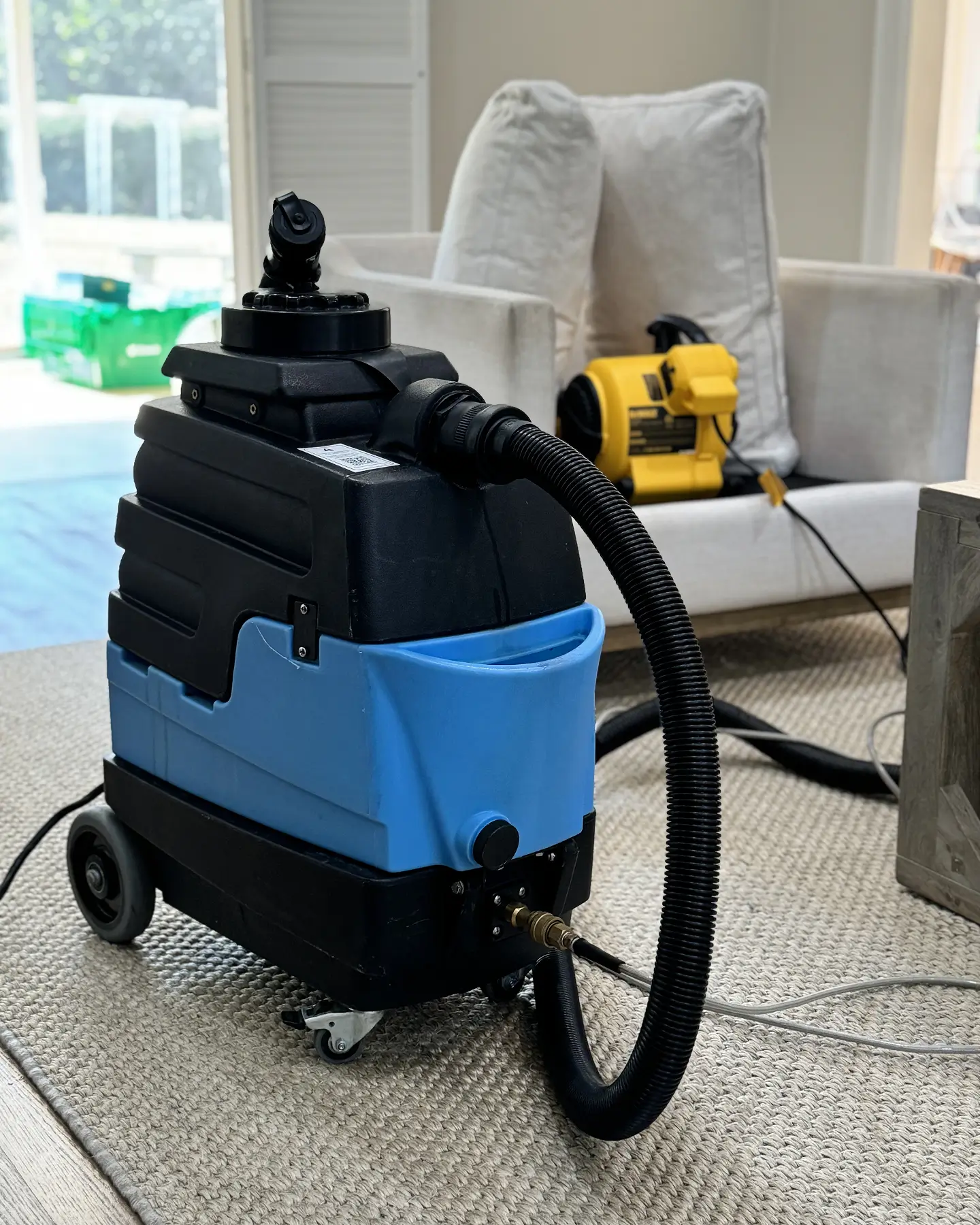 Extractor and yellow air mover set up for quick drying after upholstery cleaning in a Denver home living room