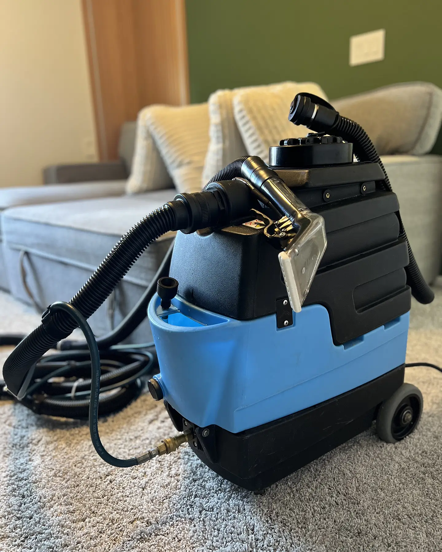 Couch Steamers extraction machine set up for upholstery cleaning beside a gray sofa